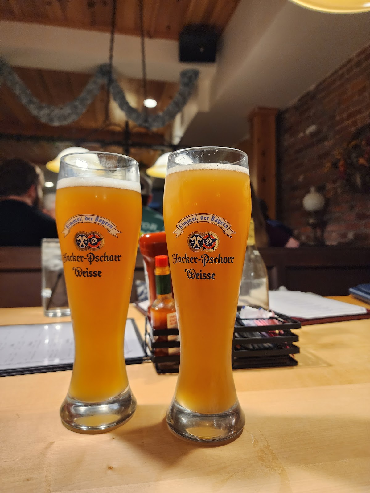 Two tall glasses of Hacker-Pschorr Weisse wheat beer in the tavern