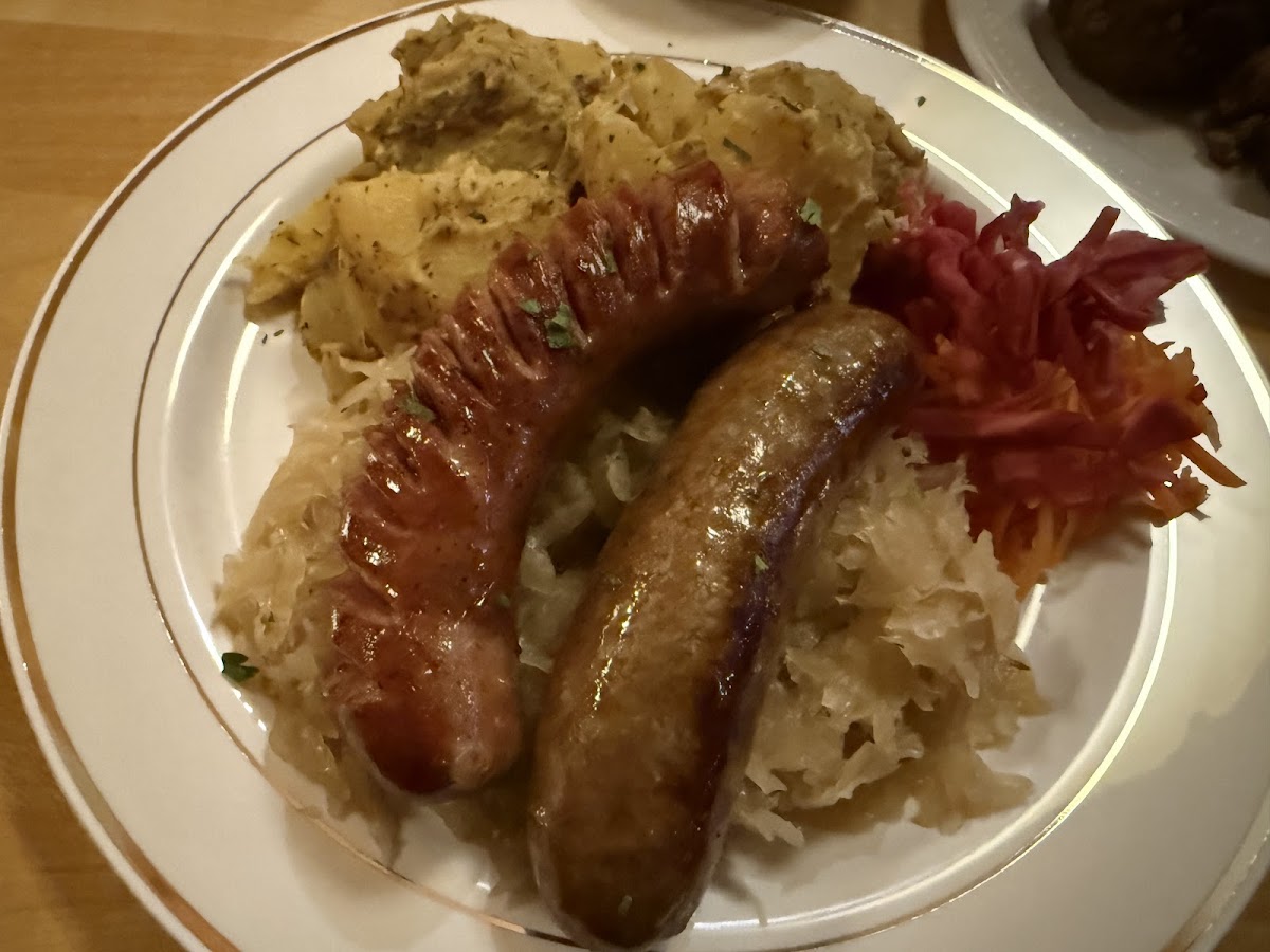 German sausage sampler over sauerkraut with potato salad